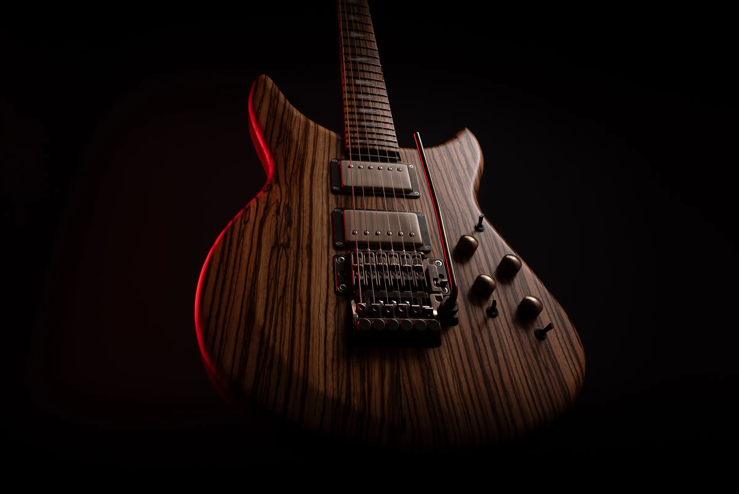 Shark electric guitar with a zebrawood body under red stage light